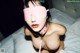 A woman wearing a pink blindfold on a bed.